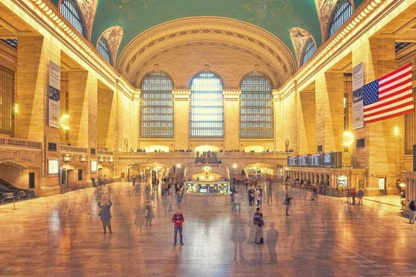 Interno della Grand Central Terminal di New York con luci calde e persone in movimento.
