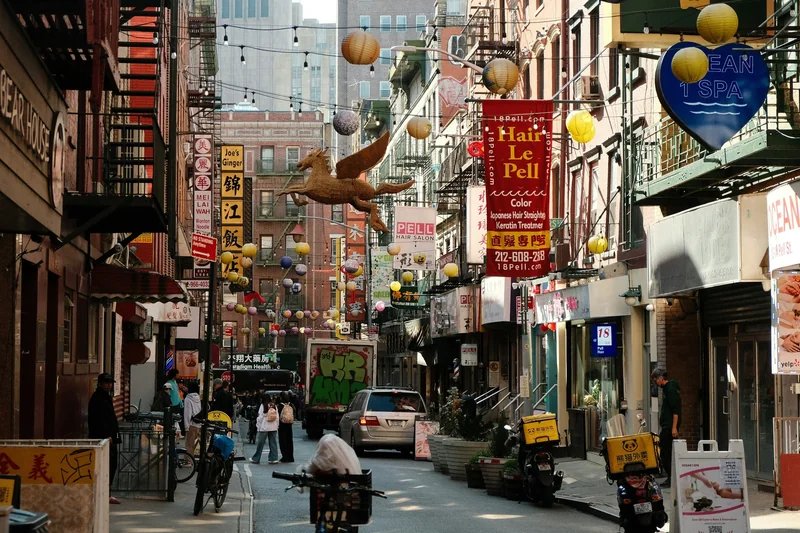 Strada di Chinatown a New York con lanterne colorate, insegne cinesi e traffico pedonale.