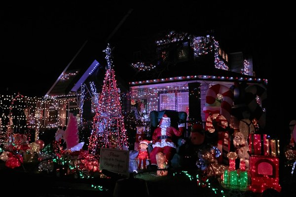 Una casa suburbana decorata generosamente con luci natalizie, un Babbo Natale gonfiabile, bastoncini di zucchero e un cartello 'non camminare sull'allestimento'.