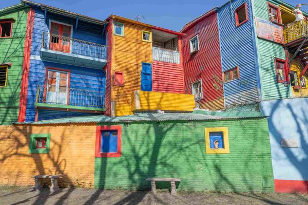 Edifici colorati di Caminito a Buenos Aires con pareti vivaci e finestre colorate sotto un cielo limpido.