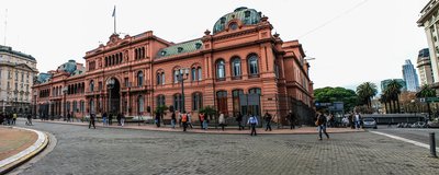 View of Casa Rosada in Buenos Aires with people walking in Plaza de Mayo.