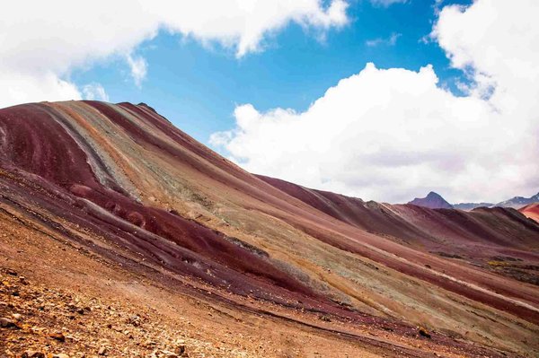Vista della Montagna Arcobaleno vicino a Cusco, Perù, con strati multicolori e cielo blu.