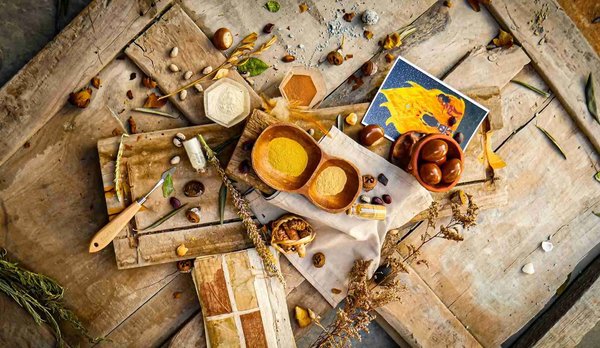 Ingredienti culinari su un tavolo rustico, con spezie, semi e decorazioni, rappresentano un tour gastronomico.