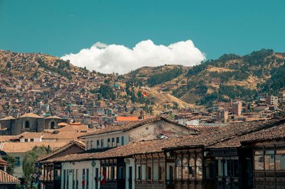 Panoramic view of Cusco with traditional rooftops and surrounding hills under a blue sky.