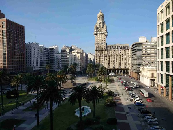 View of Plaza Independencia in Montevideo with Palacio Salvo and palm trees at the center of the square.