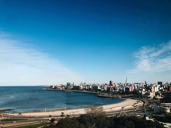 Panoramic view of Pocitos Beach in Montevideo with urban skyline and blue sky.