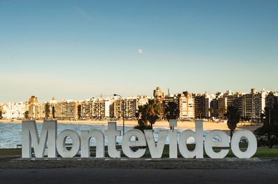 Cartello di Montevideo con skyline della città e costa sullo sfondo in una giornata soleggiata.