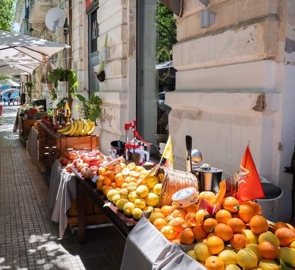 Bancarella di frutta fresca con arance, banane e altri prodotti in un mercato all'aperto a Montevideo.